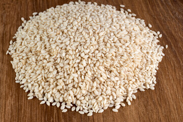 Close up of organic raw white sesame seeds on wooden background