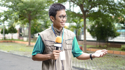 Fototapeta premium asian male journalist wear vest and ready for news