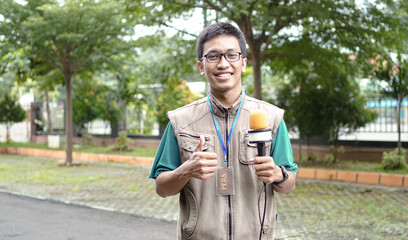 asian male journalist wear vest and ready for news. OK gesture
