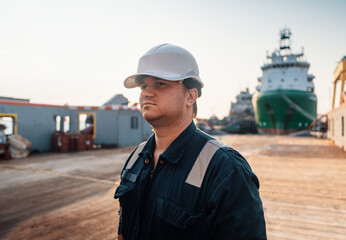 Marine Deck Officer or Chief mate on deck of offshore vessel or ship , wearing PPE personal protective equipment - helmet, coverall. Ship is on background