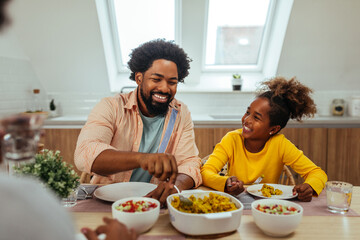 Afro father and daughter eating together at home