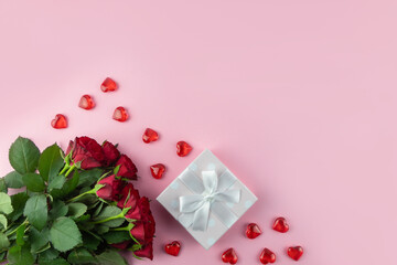 Festive background. Valentine's Day, Mother's Day, 8 March. Bouquet of red roses, box with a gift and hearts next to a pink background with place for text