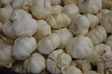 Many heads of white garlic for sale at an outdoor farmer's market.