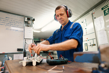 Marine electrical engineer officer in engine control room ECR. He works in workshop with electric...