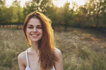 attractive woman in a white sundress resting in nature at sunset