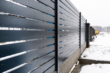 Modern anthracite panel fencing, with a visible fence foundation connector, it rains in winter, in...