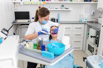 Young woman fixes her teeth by female dentist in dental office.