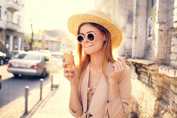 Pretty woman in sunglasses and a hat on the street walk with ice cream