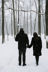 A man and a woman on the background of a snow-covered forest in a snowfall