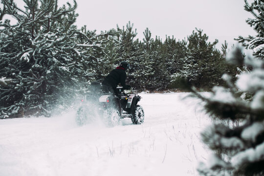 Quad bike rides through a snowy forest
