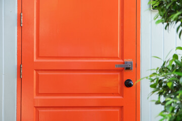 Closeup orange wood door with doorknob from outdoor view