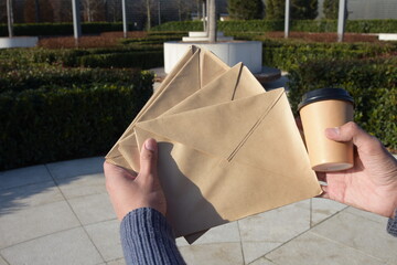 A man in the street holds envelopes with a letter.