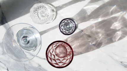 Variety of empty glasses.on gray stone background with hard shadows and sun glare. organic shadows. ,sober concept. trendy shadows and hard sunlight reflection,top view