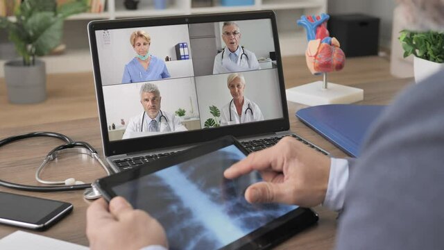 doctor having a work group video chat conference using computer,back view of male medic join an online meeting with colleagues to discuss and examine coronavirus lung x-ray disease on laptop screen 
