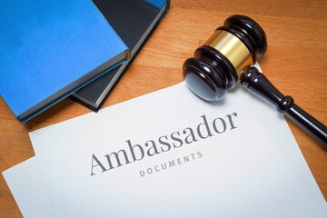 Ambassador. Document with label. Desk with books and judges gavel in a lawyer's office. - obrazy, fototapety, plakaty