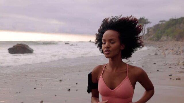 Athletic Somali woman jogging on the beach in Malibu California. Slow motion.