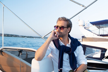 Handsome man wearing sunglasses on the yacht. Portrait of smiling man on sailing boat at sunset in...