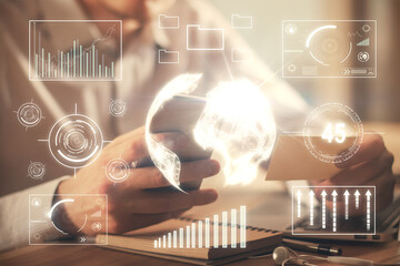 Double exposure of man's hands holding and using a phone and financial graph drawing. Analysis...