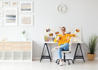 Cheerful woman sitting with coffee in home office