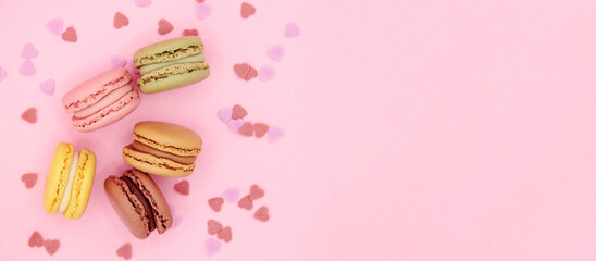 Top view macaroons with little hearts on pink background with space for text. Valentines day concept banner, love, surprise, food delivery, sweet table menu