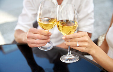love, dating and people concept - close up of couple clinking wine glasses and celebrating engagement at restaurant
