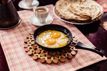 Elegant Restaurant Plate of Fried Eggs Decorated with Fresh Spinach Leaves and Young Pea Shoots on Flat Black Plate. Macro Photo of Healthy Nutritious Breakfast Isolated on White Background
