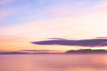 Fototapeta na wymiar Misty lake landmark at dusk with orange blu sky and purple soft blurry clouds 