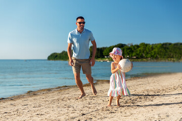 family, leisure and people concept - happy father and baby daughter playing ball on summer beach
