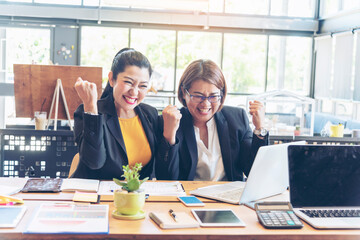 Fototapeta na wymiar Happy success business woman partner working together in company office corporate executive teamwork. Meeting Executive Asian business woman using laptop office desk with fist arm raised win happiness