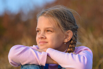 Portrait of a beautiful ten-year-old girl looking at the sunset, close-up