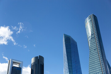 Obraz premium View of four modern skyscrapers with a blue sky and some clouds. Space for text. 