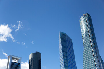View of four modern skyscrapers with a blue sky and some clouds. Space for text. 