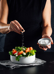 Woman preparing a salad with tomatoes, lettuce, olive oil and salt