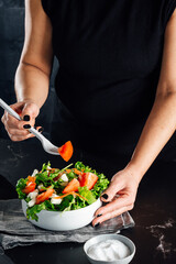Woman preparing a salad with tomatoes, lettuce, olive oil and salt