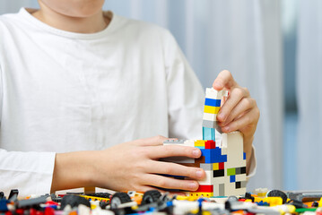 young boy playing with plastic construction toys at home.
