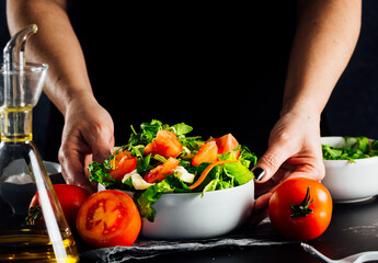 Woman preparing a salad with tomatoes, lettuce, olive oil and salt