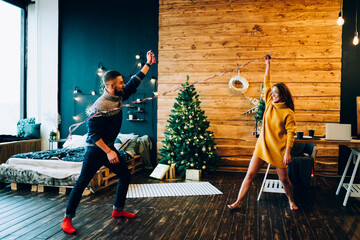 Funny young couple messing around with Christmas serpentine
