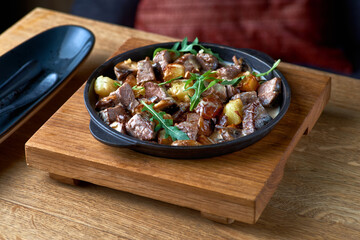 Traditional Swiss dish Veal with potatoes in a creamy sauce close-up on a forged frying pan