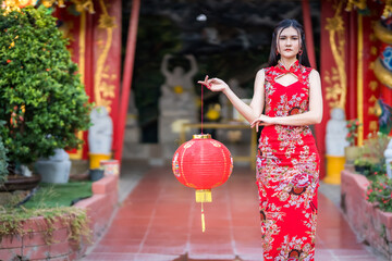 Asian woman wearing red traditional Chinese cheongsam decoration hold paper lanterns with the...