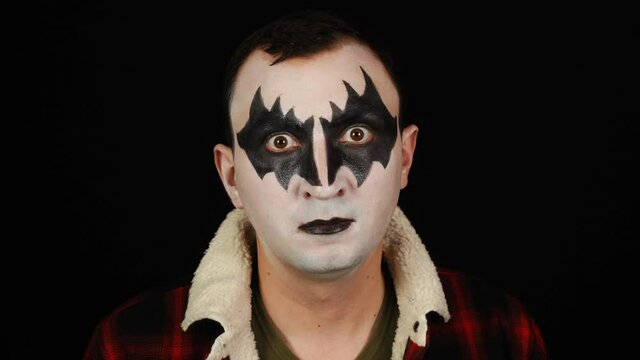 Man in demon makeup with crazy look on black background