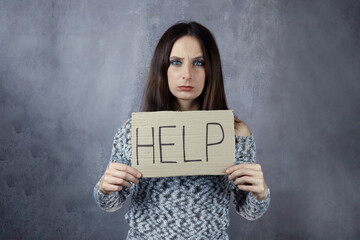 Naklejka premium Cardboard with word help in hands of young woman
