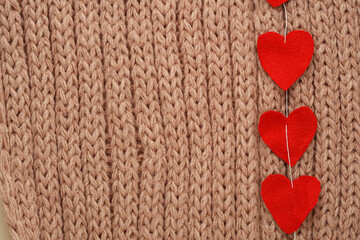 Obraz premium Hearts cut from fabric on a thread, on a knitted background. Valentine day card