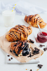 croissants with chocolate filling and strawberry jam on a white table close-up