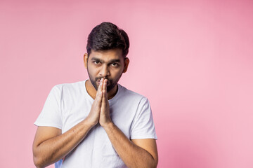 Portrait of handsome Indian guy standing on pink background