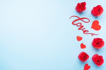 The word Love and red hearts roses on a blue background, top view. Holiday card for Valentine's Day. Flat lay.