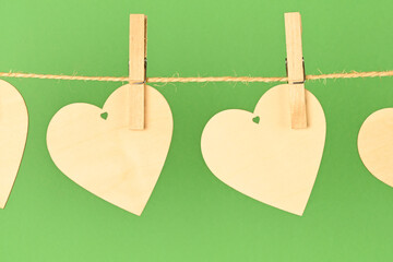 Valentine background. 2 wooden hearts hung with rope on a green background. Valentine concept. Flat view, top view, copy space