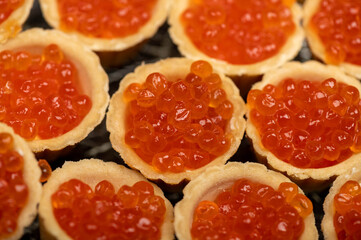 Tartlets with salmon caviar on a platter. Close-up, selective focus.
