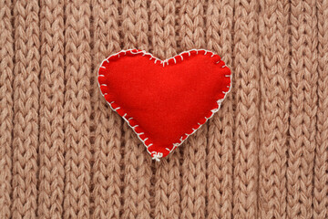 Red heart sewn from fabric on a knitted background. Valentine day card