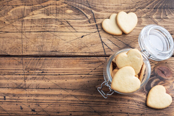 Homemade cookies in the shape of hearts in a glass jar, wooden background. The concept of Valentine's Day. copy space.