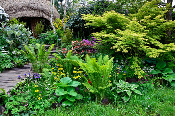 A tropical bog garden with thatched building and exotic plants and flowers